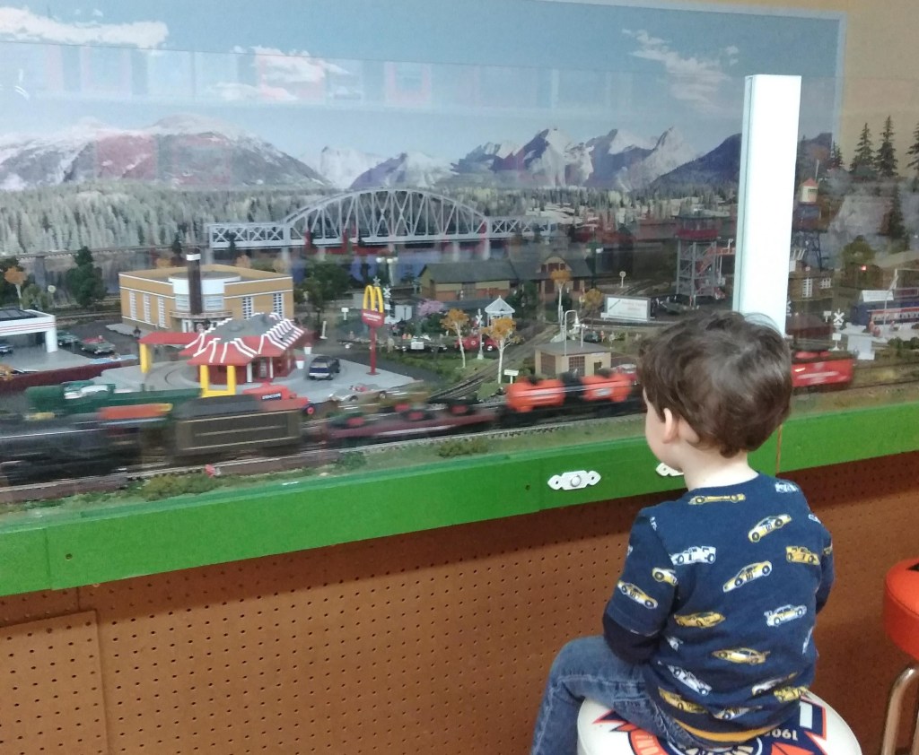 small boy looking at a model train set